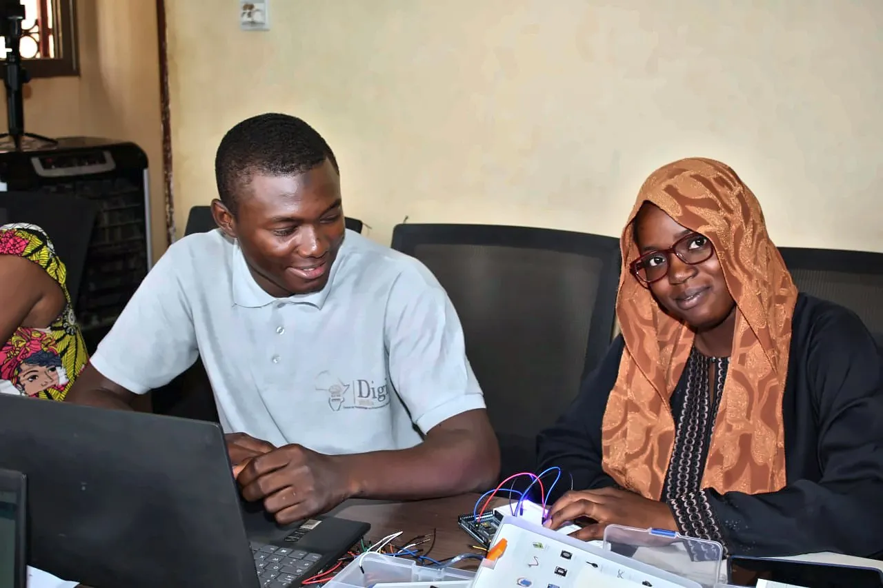 Un formateur DigitAfrika et une apprenante, souriants, pendant un atelier Arduino à Ségou