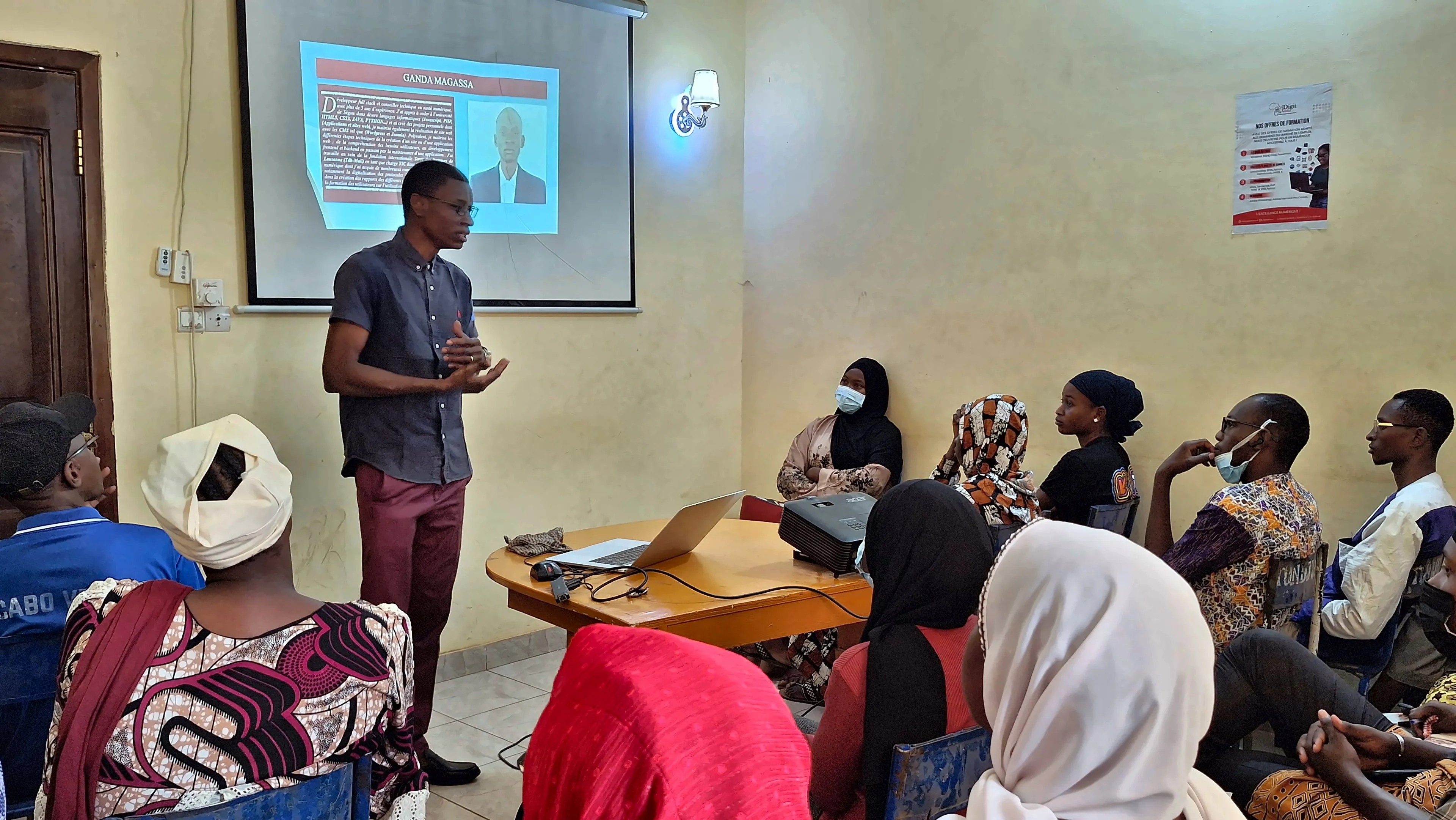 Ganda Magassa présente une session devant les apprenants, diaporama projeté au mur